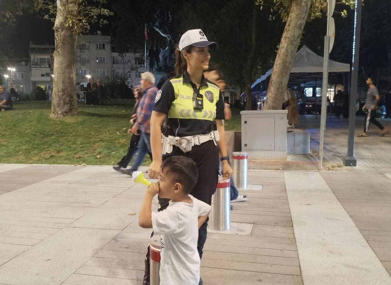 Bursa'da parkta kaybolan çocuğu bulan kadın polis memuru, çocukla birlikte parkta duruyor.