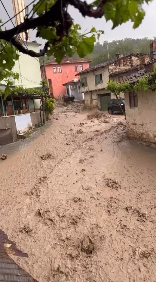 Bursa Keles Davutlar Mahallesi'nde sel sonrası çamurlu suyla kaplı sokak, evler.