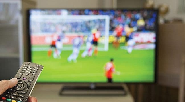 Televizyonda futbol maçı izleyen bir el ve kumanda.