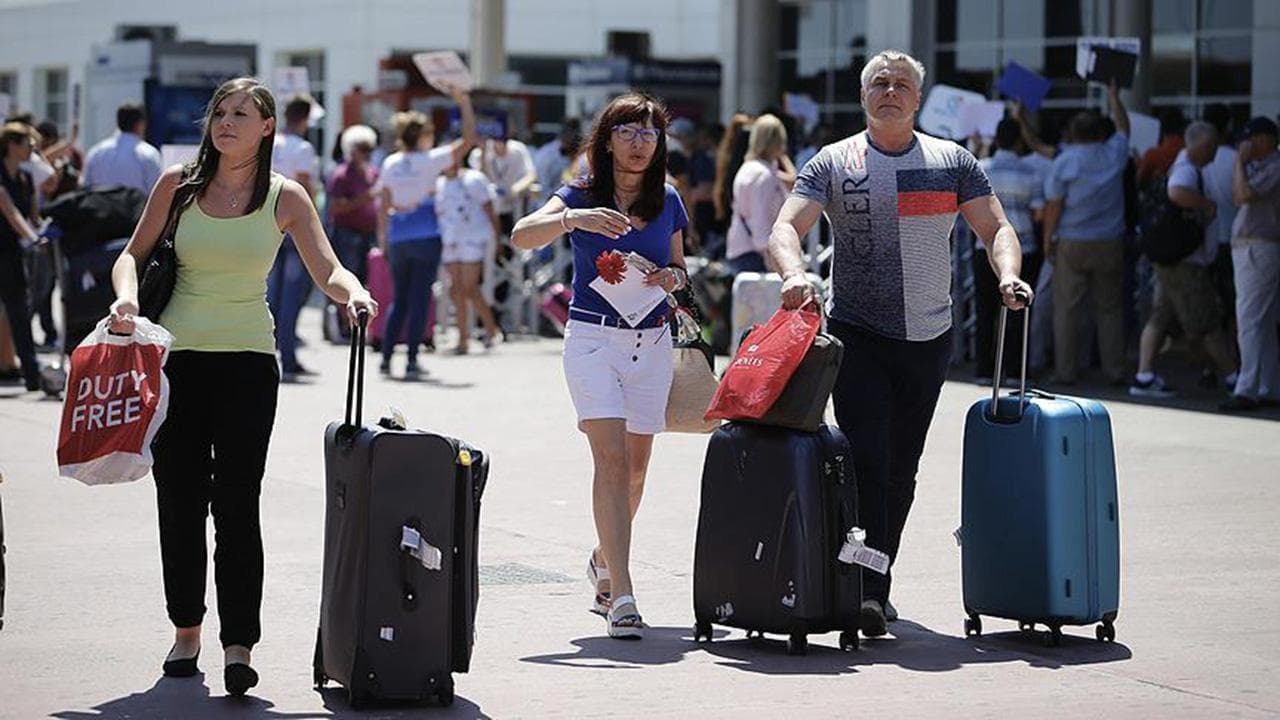 Havaalanında valizleriyle yürüyen bir grup turist.