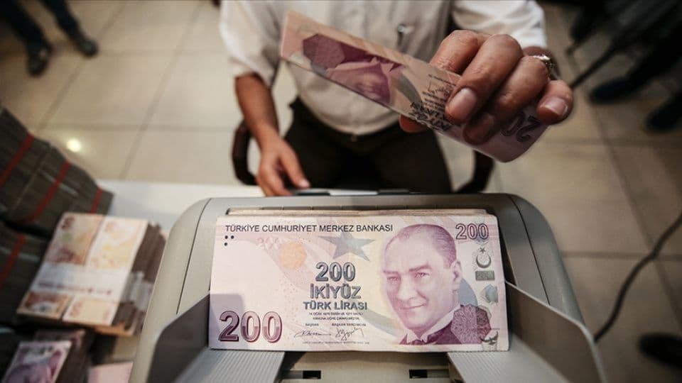Türk Lirası banknotları ve para sayma makinesi, finansal işlemler.
