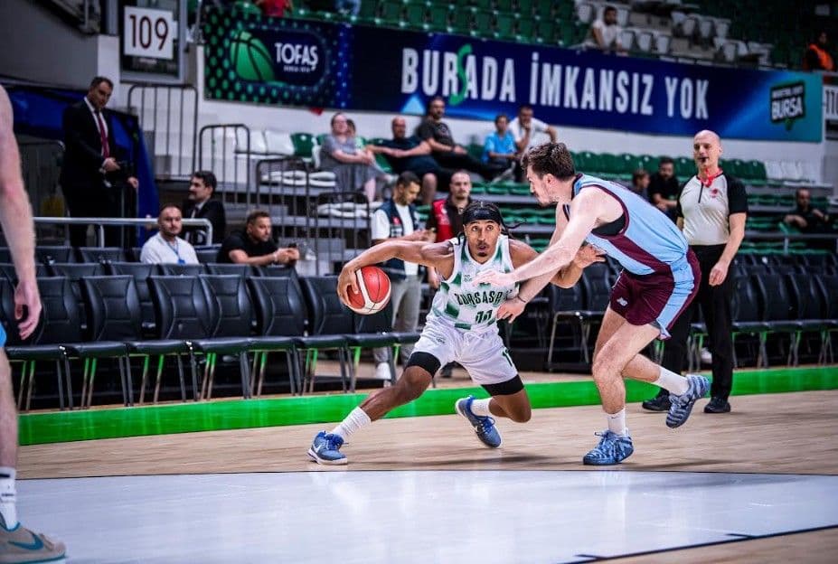 Bursaspor Basketbol ve Trabzonspor arasındaki maçtan bir an, oyuncular top sürme mücadelesinde.