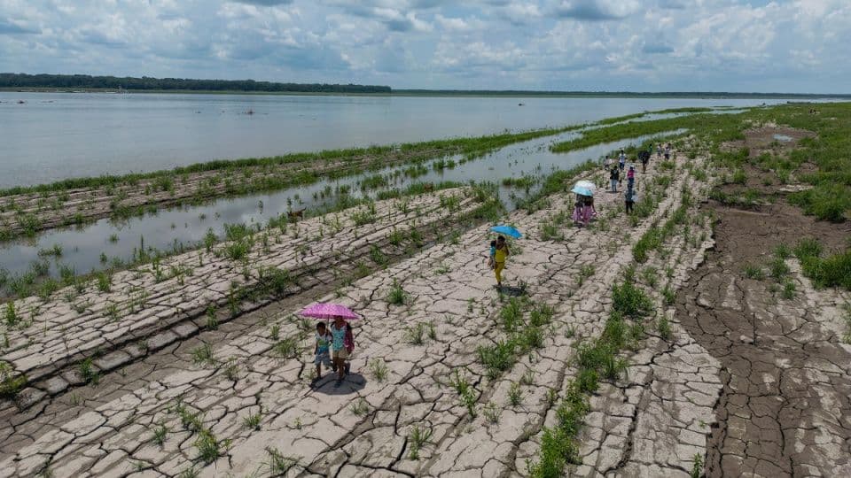 El Nino'nun neden olduğu kuraklık ve düşük su seviyeleri, çatlamış topraklar üzerinde yürüyen insanlar.