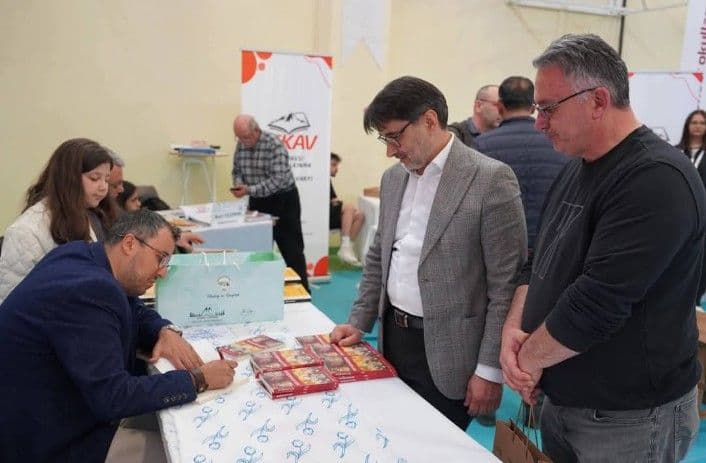 Keles Kitap Günleri etkinliğinde bir yazar, okuru için kitabını imzalıyor.