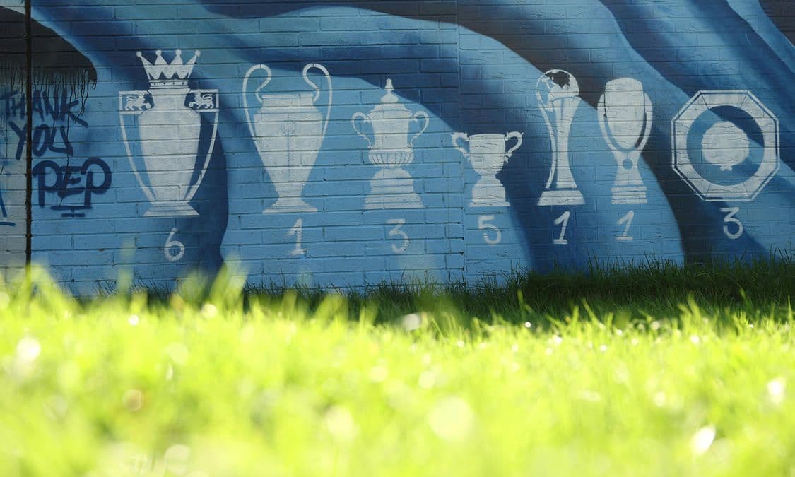 Manchester City'nin kazandığı Premier Lig, Şampiyonlar Ligi ve diğer kupaları gösteren duvar grafiti.