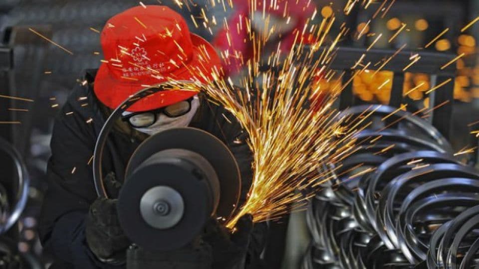 Çin'de bir fabrikada metal parçalar üzerinde kıvılcımlar çıkararak çalışan bir işçi.