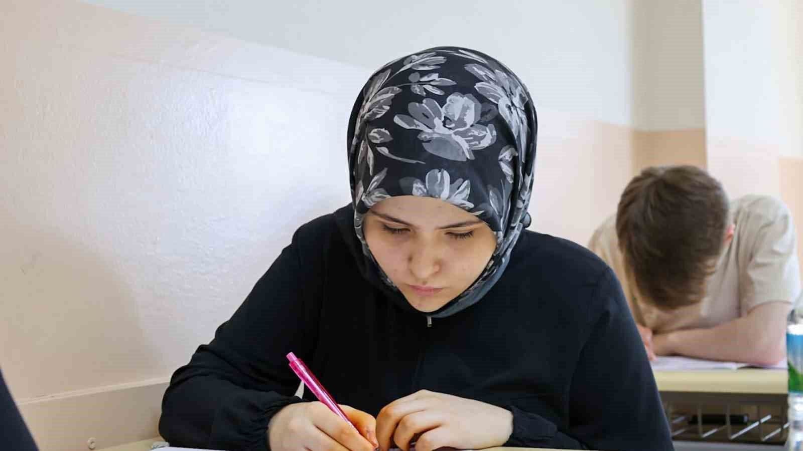 YKS sınavında kalemle kağıda yazı yazan öğrenci.
