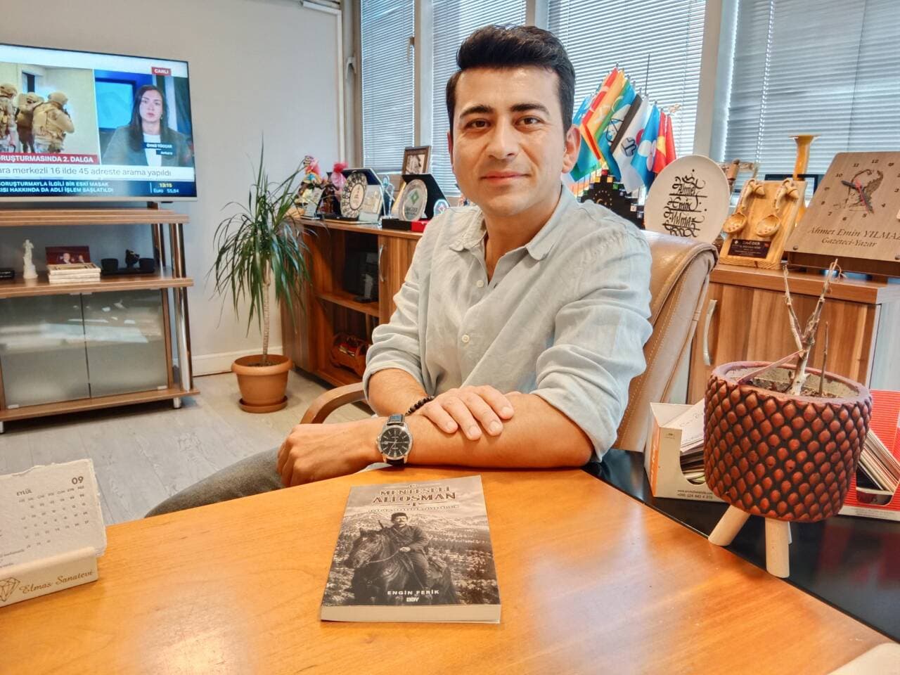 Yazar Engin Ferik, "Menteşeli Ali Osman" adlı kitabıyla masasında oturuyor.