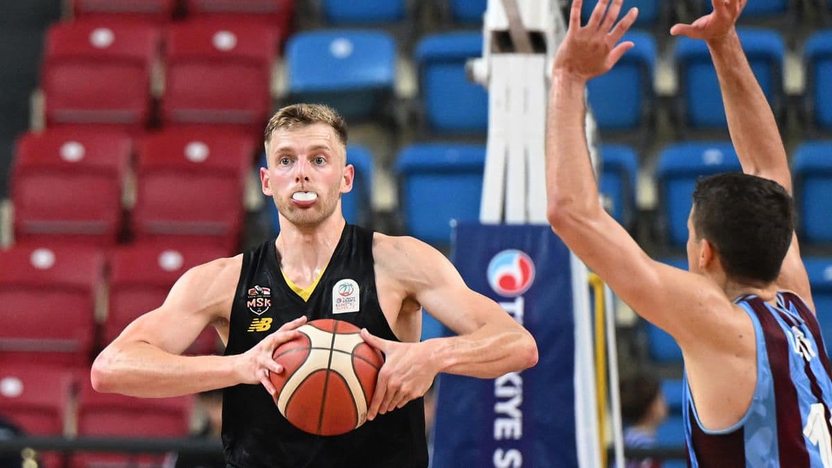 Mersinsporlu basketbolcu maç sırasında topu tutarken, rakip oyuncu savunmada.