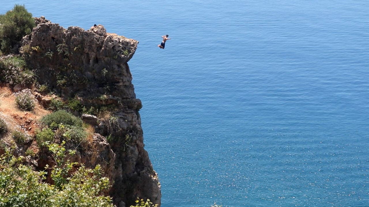 Antalya Konyaaltı falezlerinden denize atlayan bir kişi.
