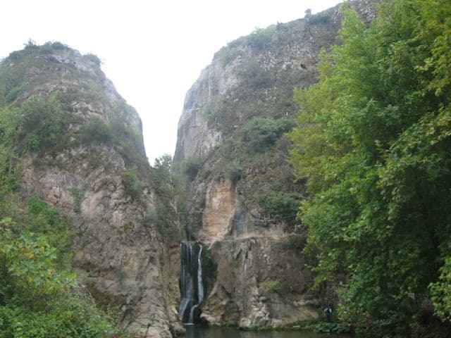 Yarhisar Şelalesi, kayalık bir kanyonun ortasında yemyeşil ağaçların arasında akıyor.