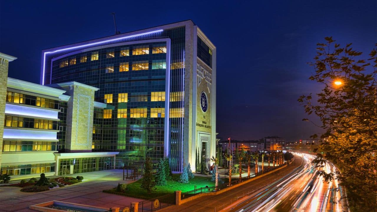 Bursa Büyükşehir Belediyesi binası gece ışıklarıyla aydınlatılmış.