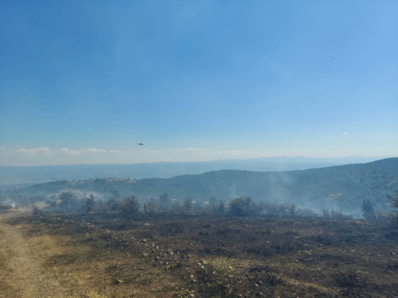 Kastamonu'da orman yangını sonrası dumanlar ve havadan müdahale eden helikopter.