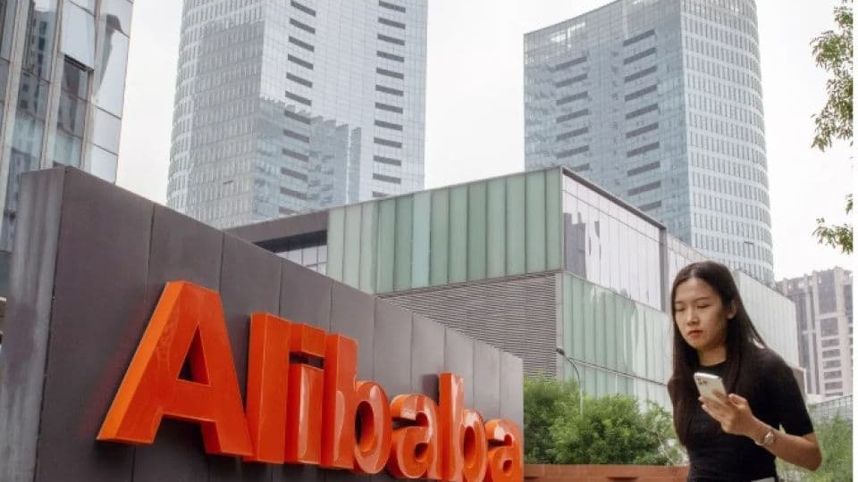 Alibaba logosu ve önünden geçen bir kişi, Çin'deki e-ticaret devinin finansal durumunu temsil ediyor.