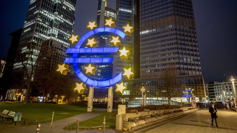 Gece vakti aydınlatılmış Avrupa Merkez Bankası binası önündeki büyük Euro sembolü heykeli.