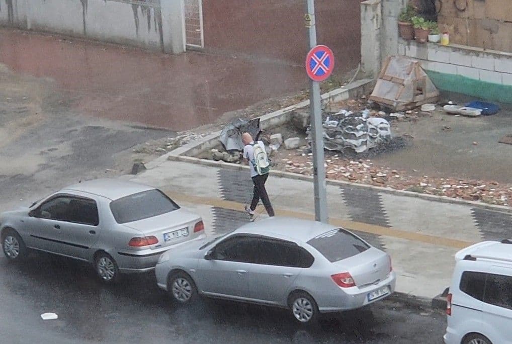 İstanbul'da sağanak yağış altında yürüyen bir kişi ve ıslak cadde.