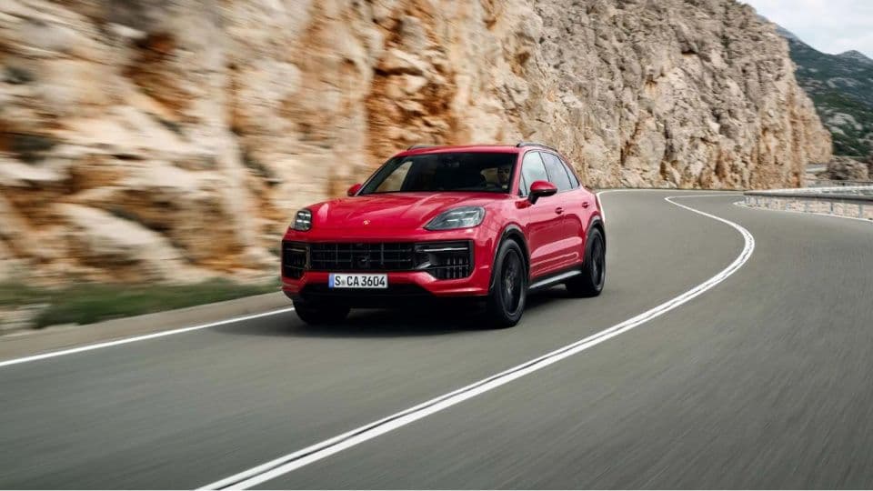 Kırmızı Porsche Cayenne Coupe, dağlık bir yolda sürüş halinde.