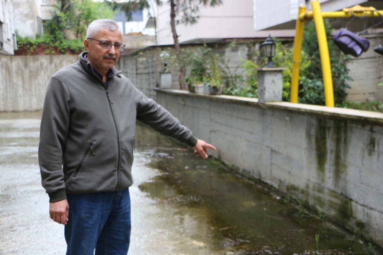 Samsun'da Mert Irmağı ıslah çalışmaları sonrası su basan evlerin önünde duran bir vatandaş, parmağıyla su seviyesini işaret ediyor.