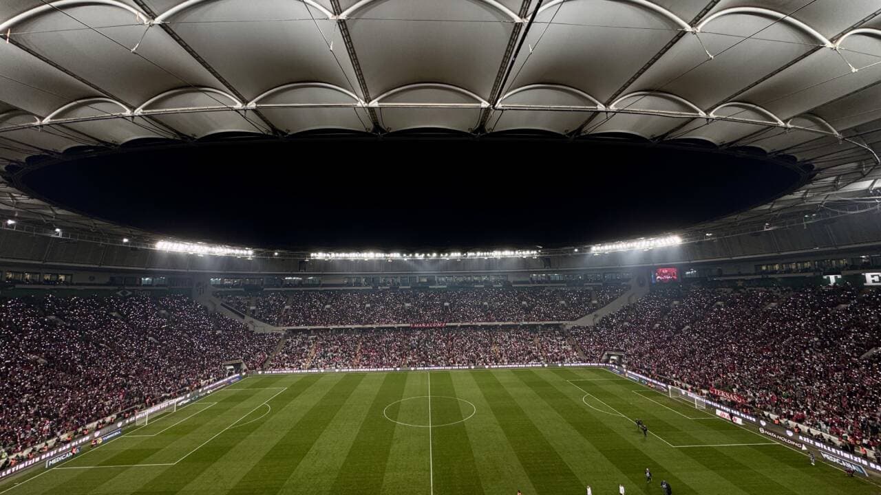 Bursa'daki bir futbol stadyumunda gece maçı atmosferi, tribünler dolu.