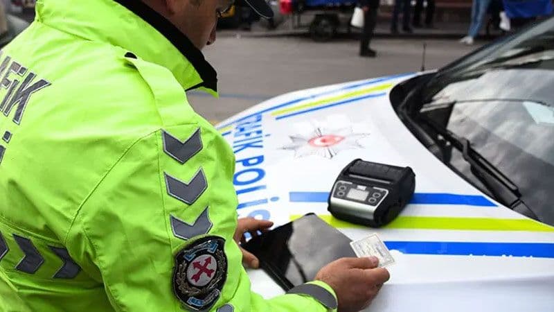 Trafik polisi, denetim sırasında evrak kontrolü yapıyor.