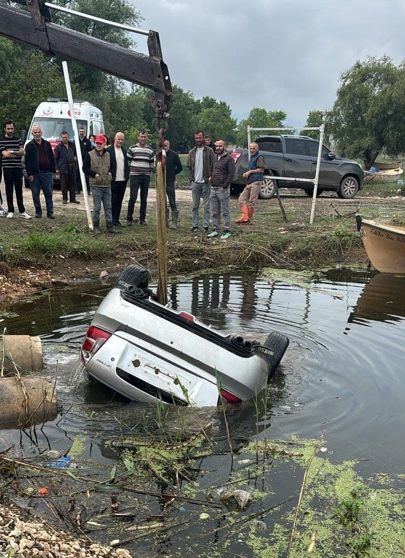 Bursa Ulubat Gölü'ne düşen otomobilin vinçle sudan çıkarılma anı, çevredeki ekipler ve vatandaşlar.
