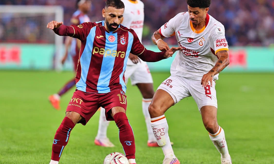 Trabzonsporlu ve Galatasaraylı futbolcular maç sırasında top kapma mücadelesi veriyor.