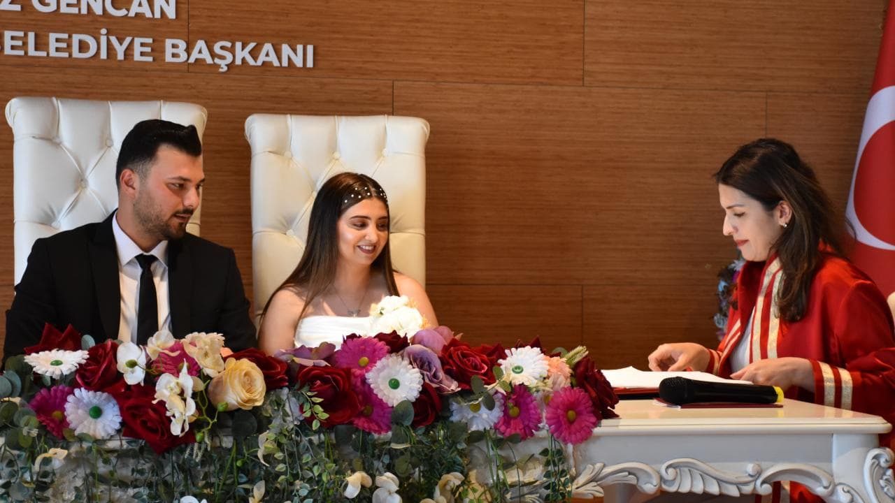 06.06.2026 tarihinde nikah masasında evlenen mutlu bir çift ve nikah memuru