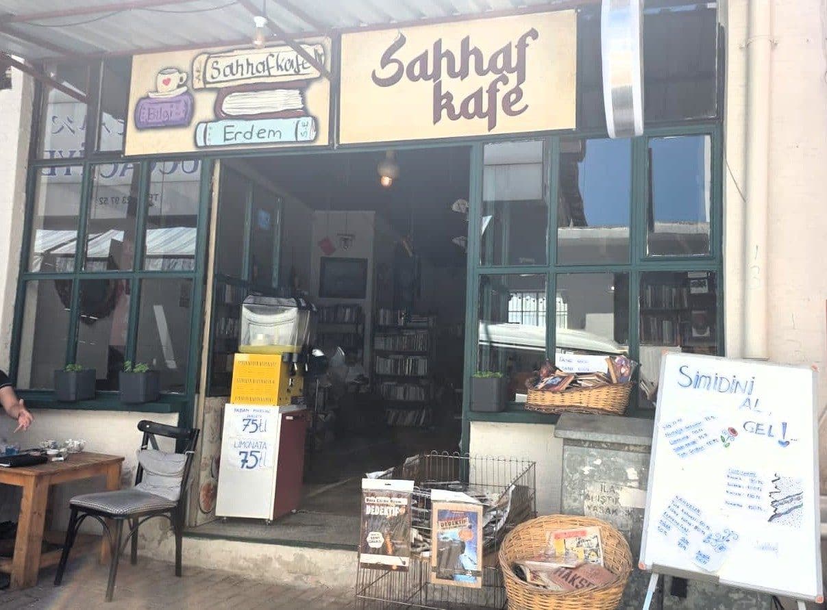 Bursa'da bulunan Sahhaf Kafe'nin dış cephesi, tabelası, camları ve girişi görünüyor. İçeride kitap rafları ve dışarıda oturma alanı mevcut.