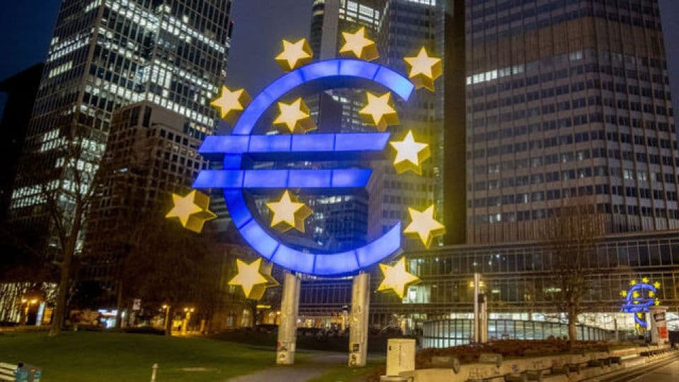 Frankfurt'taki Avrupa Merkez Bankası binası önünde gece aydınlatılmış Euro sembolü heykeli.