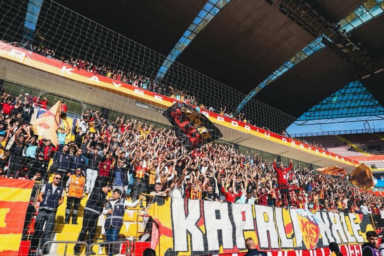 Kayserispor taraftarları tribünde tezahürat yaparken, güvenlik görevlileri sahayı izliyor.