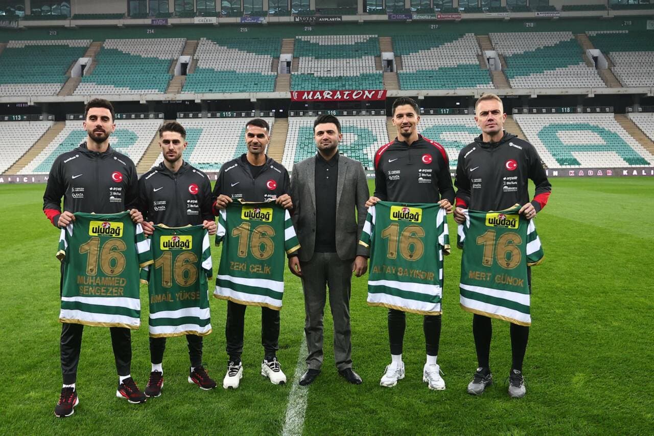 Milli futbolcular Altay Bayındır, Zeki Çelik, Mert Günok ve diğerleri, stadyumda Bursaspor formalarıyla poz veriyor.