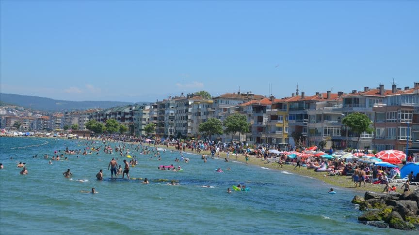 Bursa'da yaz aylarında kalabalık bir halk plajında yüzen insanlar ve sahil şeridi.