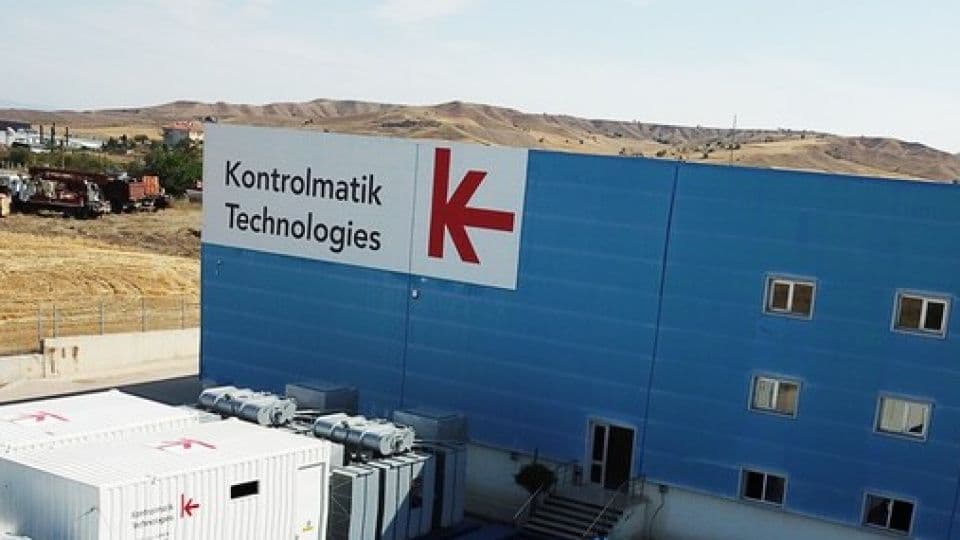 Kontrolmatik Teknoloji'nin mavi renkli fabrika binası ve logosu.