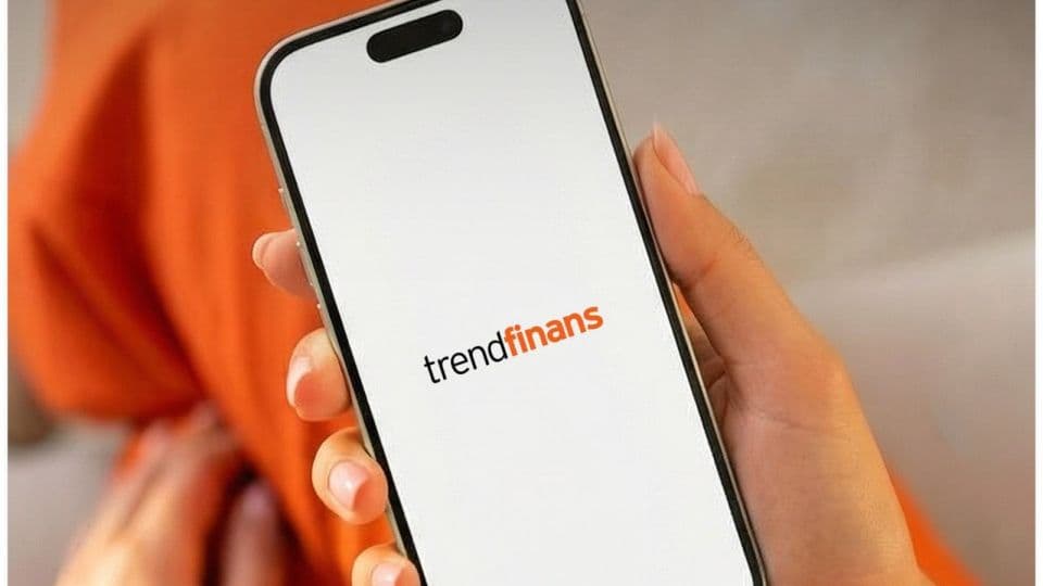 Bir elin tuttuğu akıllı telefon ekranında TrendFinans logosu.