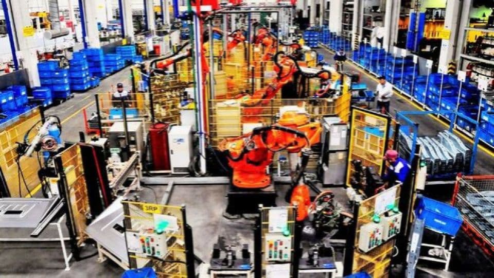 Üretim bandında robotik kolların çalıştığı fabrika.