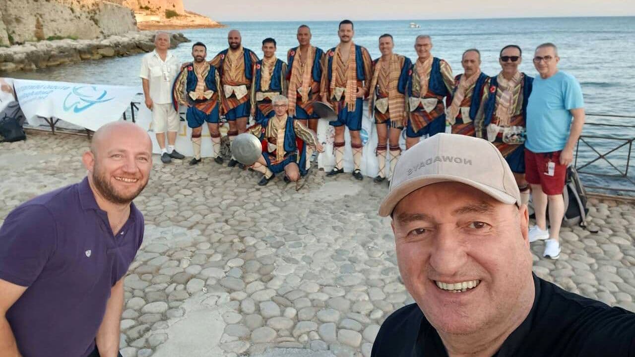 Bursa Kılıç-Kalkan ekibi, İtalya'da geleneksel kıyafetleriyle deniz kenarında poz veriyor.