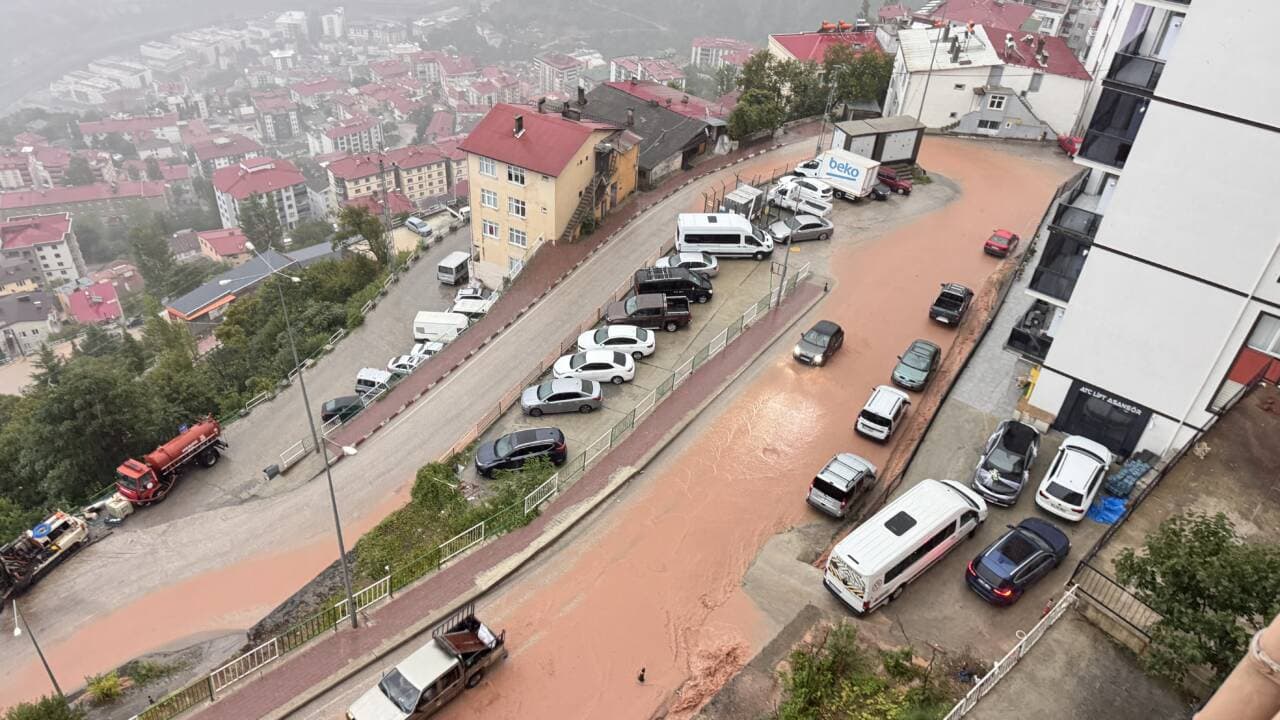 Artvin'de şiddetli sağanak sonrası sel sularıyla kaplanmış çamurlu bir cadde ve park halindeki araçlar.