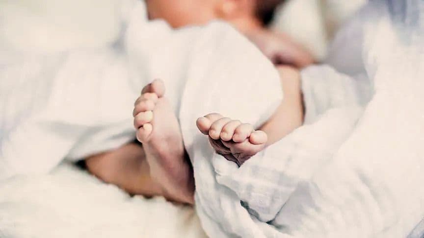 Bursa'da en çok tercih edilen bebek isimleri haberini temsil eden, beyaz battaniyeye sarılı bir bebeğin ayakları.
