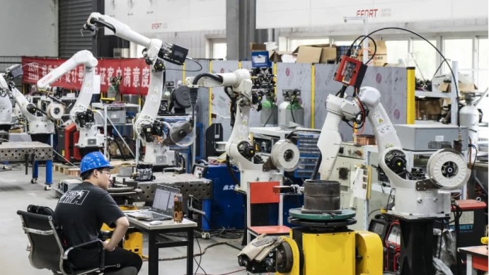 Sanayi üretim tesisinde çalışan bir mühendis ve robotik kollar.