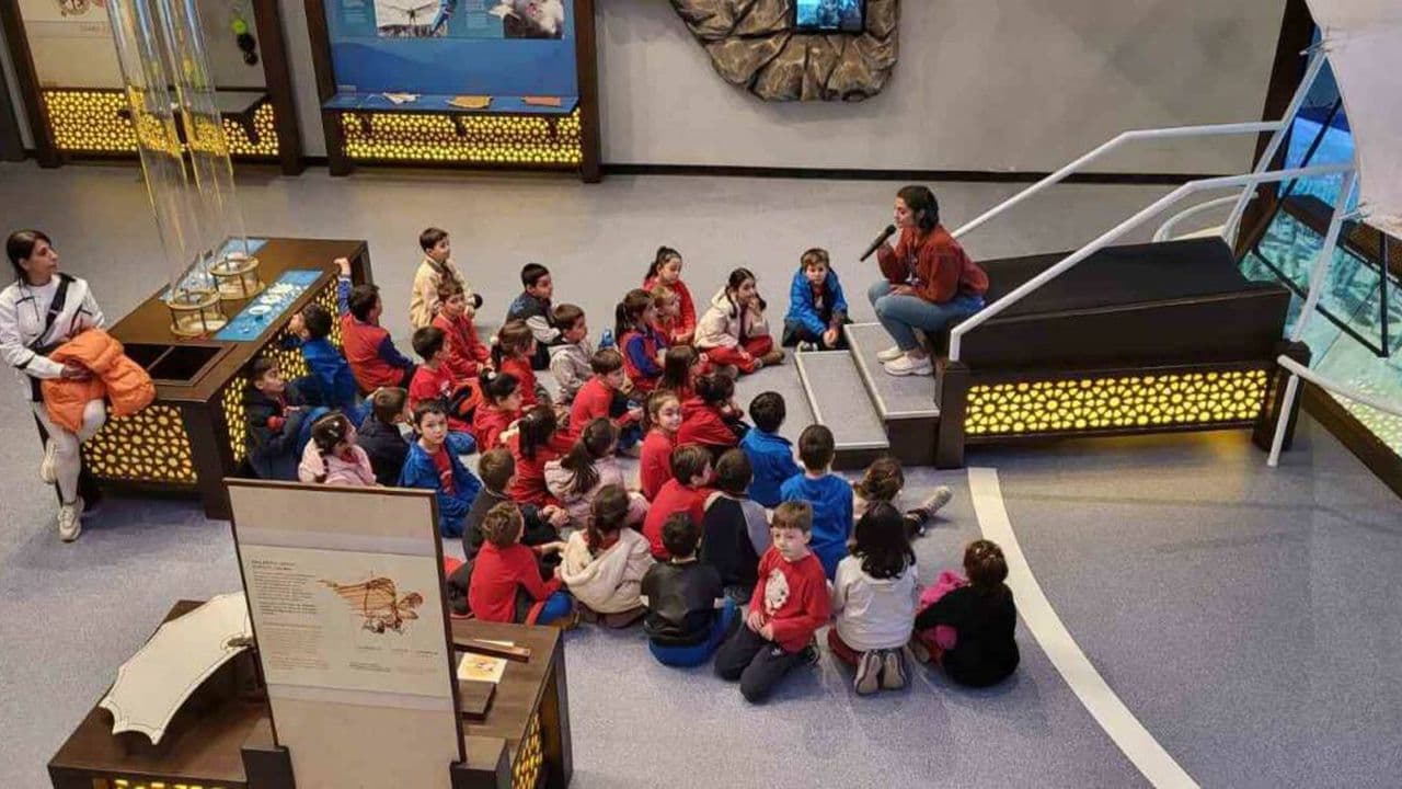Bursa'da bir grup ilkokul öğrencisi, uzay ve havacılık merkezinde eğitmenlerini dinlerken görülüyor.