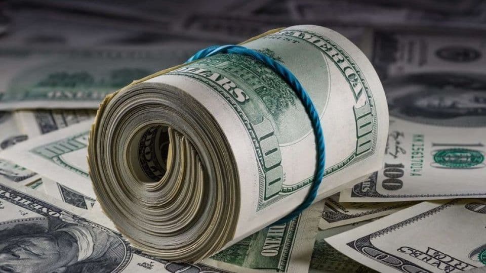 Dolar banknotlarından oluşan rulo ve etrafa yayılmış banknotlar