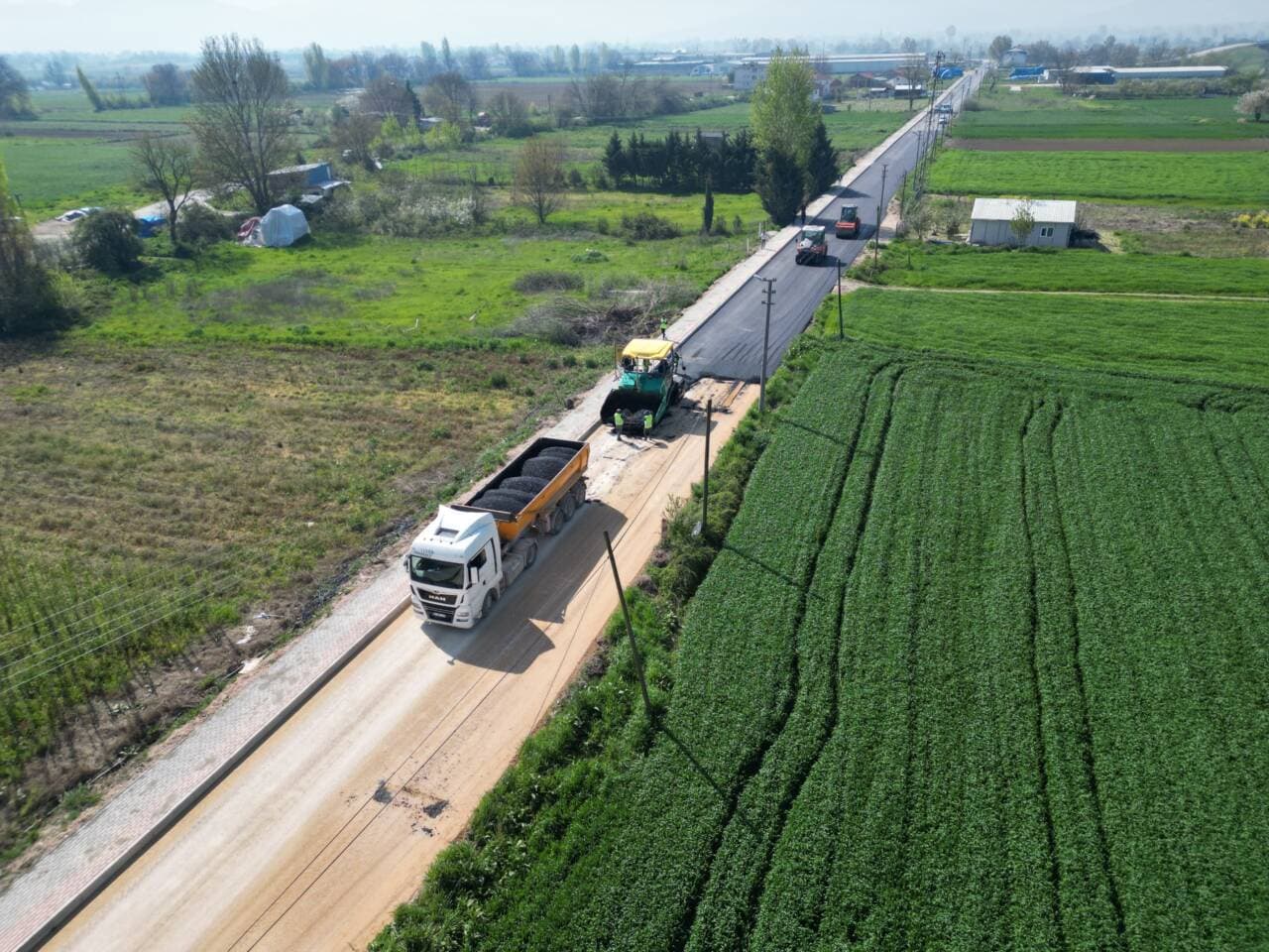 Bursa İnegöl Kulaca bağlantı yolu asfaltlama çalışmaları, iş makineleri ve kamyonlar.