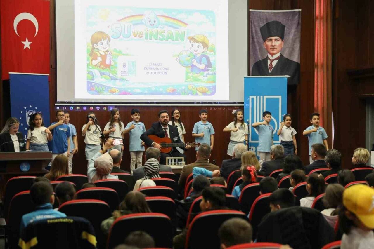 Bursa'da su tasarrufu eğitimi alan öğrenciler sahnede şarkı söylerken veya gösteri yaparken.