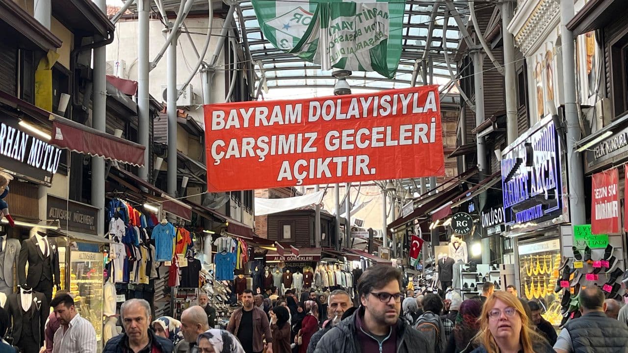 Bursa Kapalıçarşı'da bayram alışverişi yapan kalabalık, çarşının uzatılan çalışma saatlerini duyuran pankart