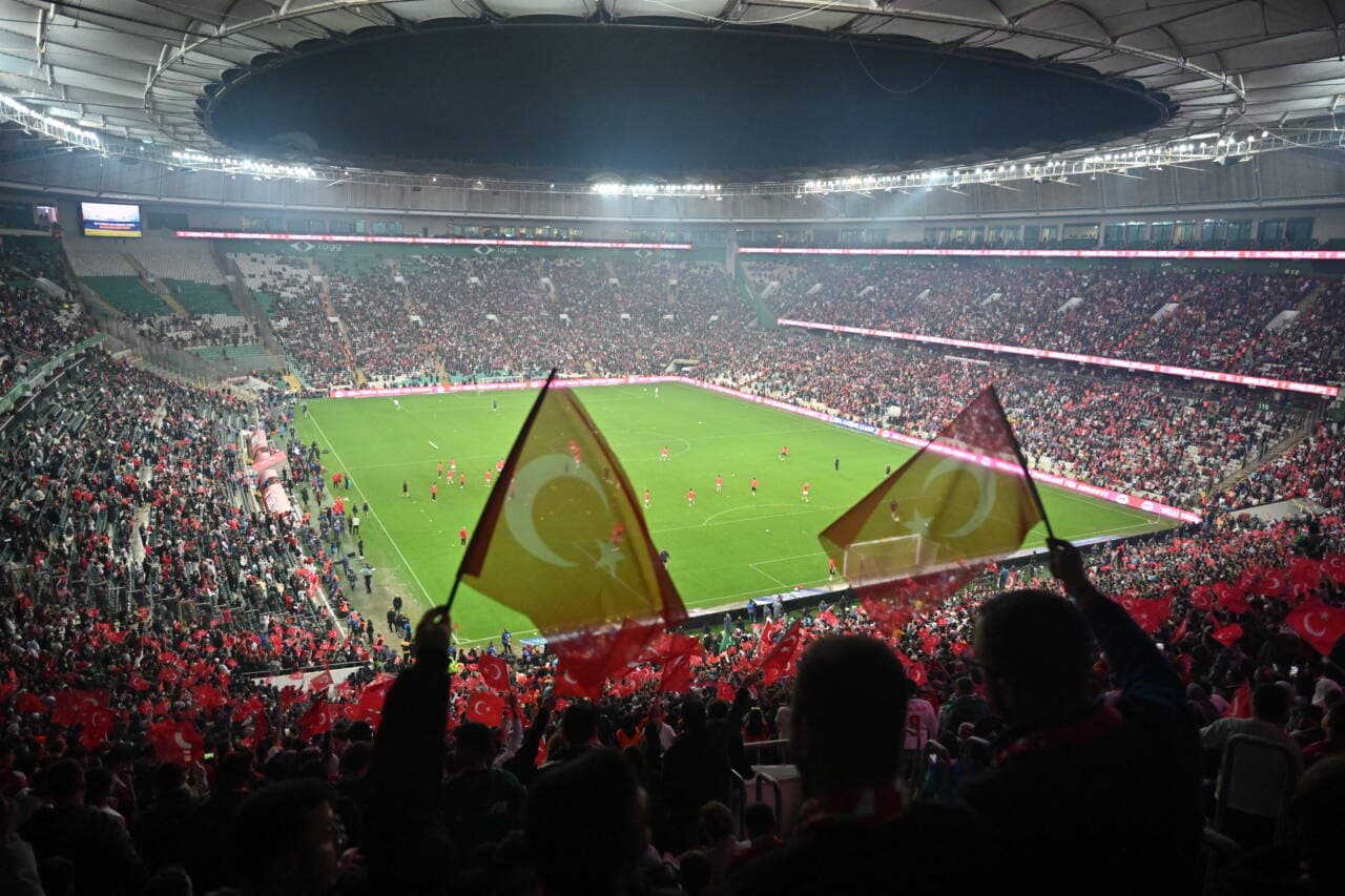 Türk bayraklarıyla dolu bir futbol stadyumunda maç atmosferi