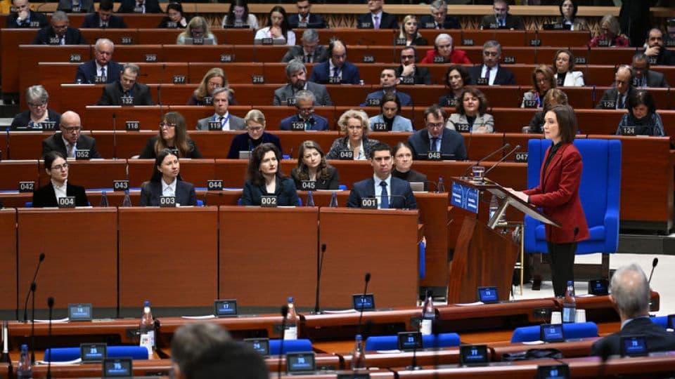 Avrupa Birliği Parlamentosu'nda bir yetkili kürsüde konuşma yaparken, parlamenterler sıralarında oturuyor.