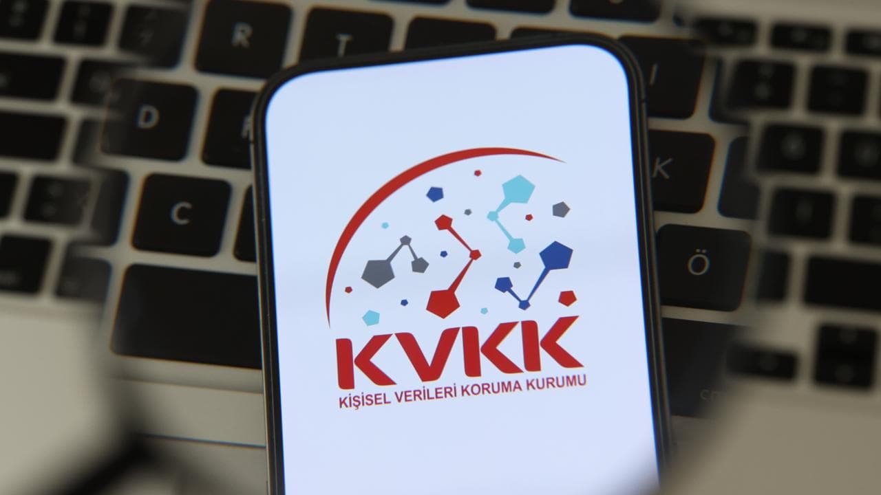 Kişisel Verileri Koruma Kurumu (KVKK) logosu bir akıllı telefon ekranında, arka planda klavye detayları.