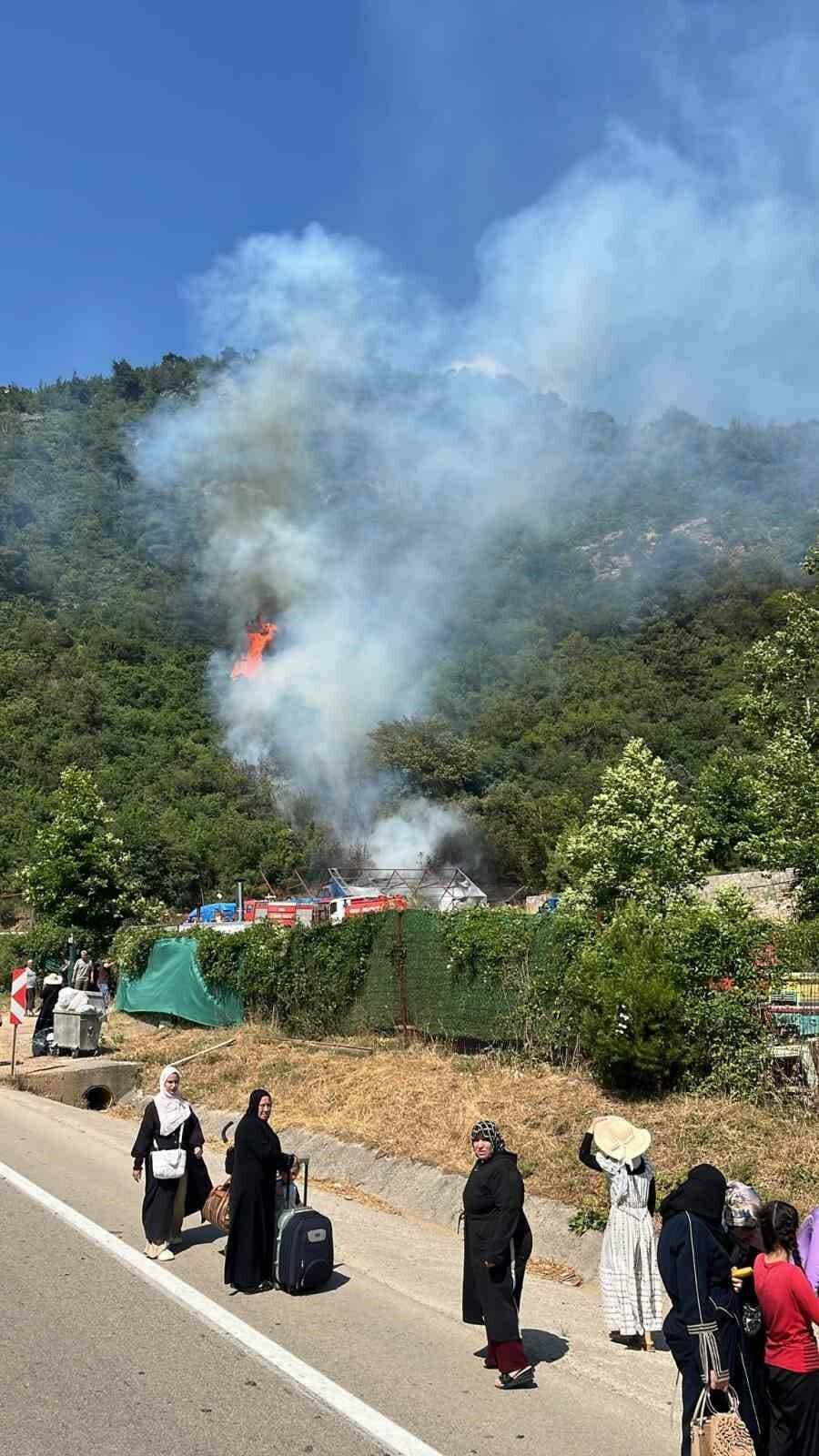 Bursa Osmangazi'de tarım arazisi yangınına müdahale eden ekipler ve yükselen dumanlar.