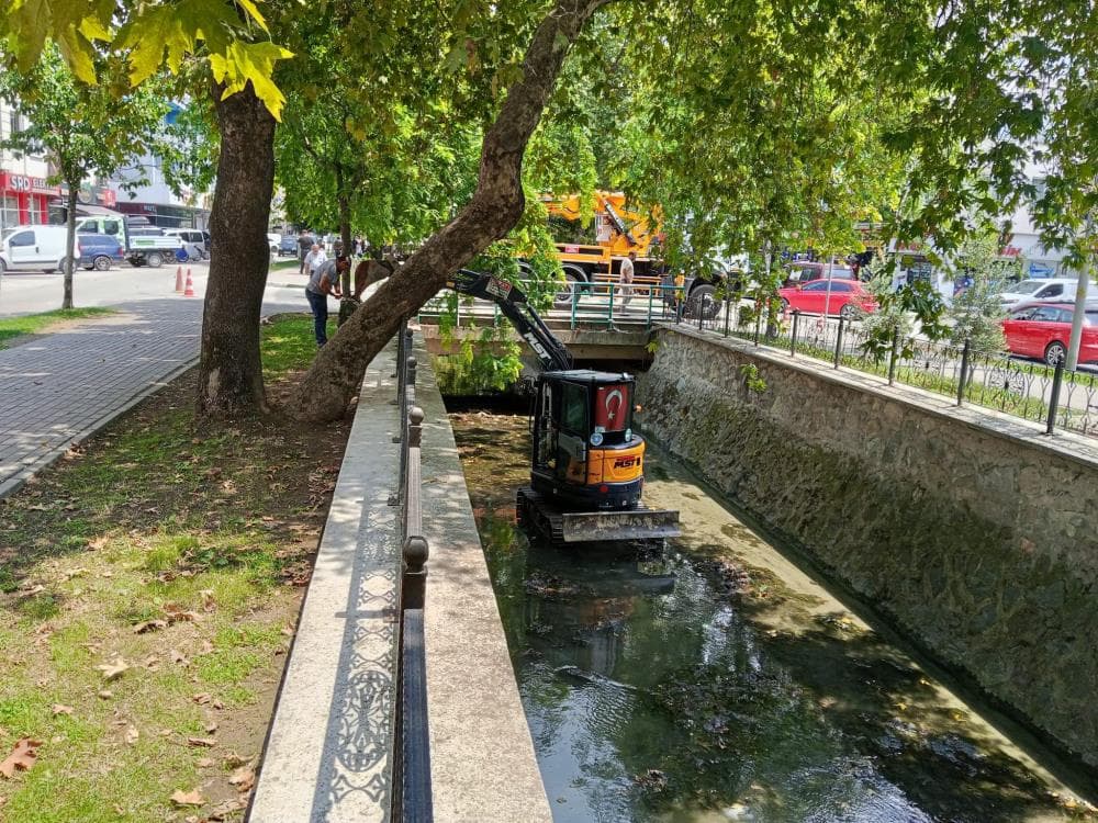Bursa'da dere temizliği yapan iş makinesi ve belediye ekipleri.