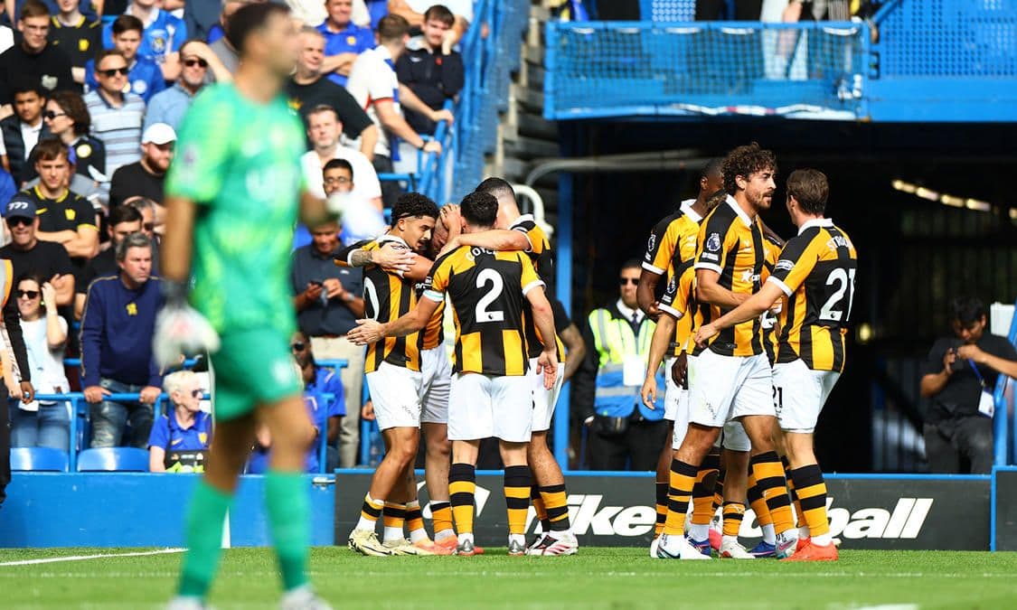 Hull City futbolcuları, bir maç sırasında gol sevinci yaşıyor. Sarı-siyah formalı oyuncular sahada birbirlerine sarılmış.